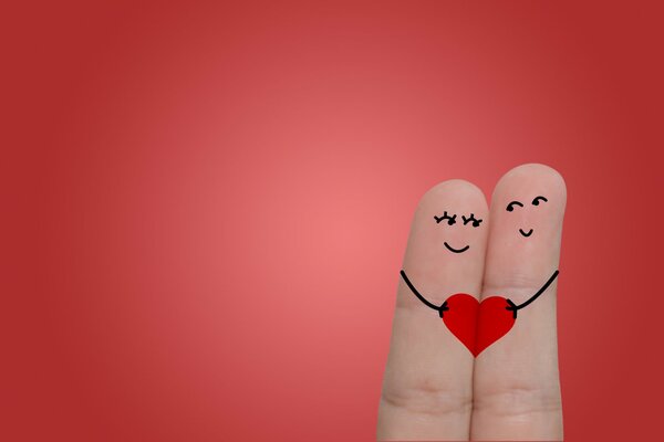 Two fingers holding a heart on a red background