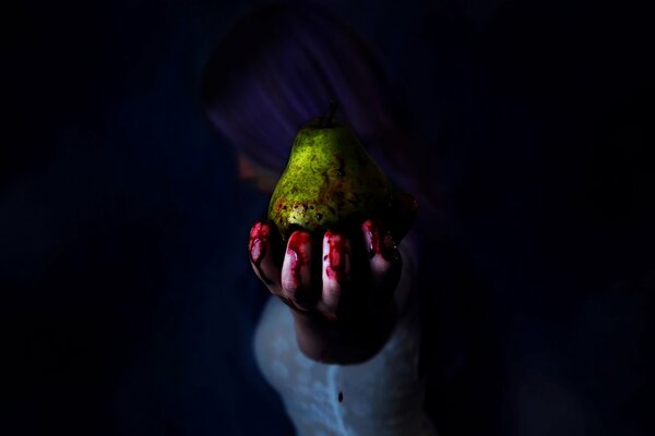The girl holds a green pear in her bloody hand