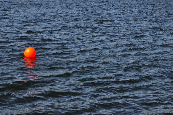 Orangefarbene Kugel auf einer Wasseroberfläche