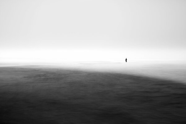 A man standing in the sea in the fog