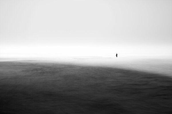 Homme debout dans la mer dans le brouillard