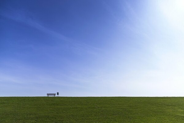 Bench on the background of the sky and a green field
