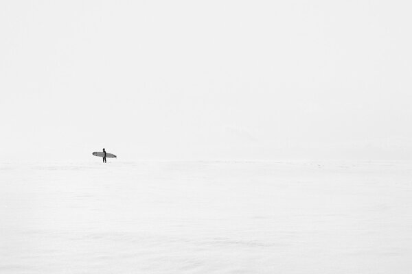 Homme avec planche dans la mer claire