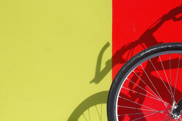 An der roten Wand ist ein Fahrradschatten zu sehen, der sein Rad trägt