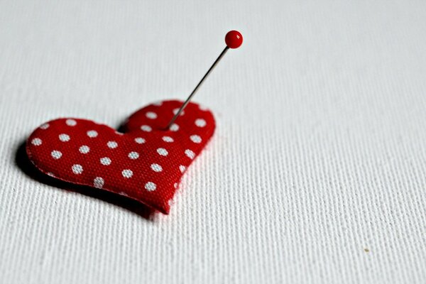 A pricked red heart forgiven by a pin