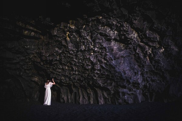 A girl in a white dress leaned against a rock