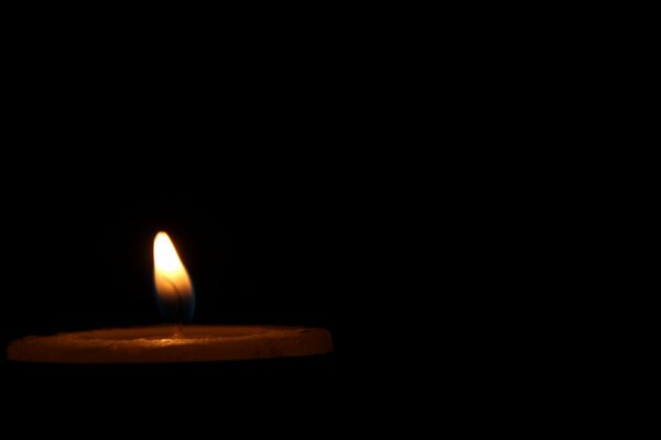 A burning candle on a black background