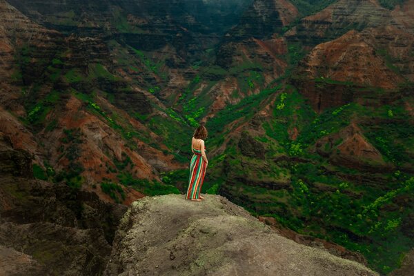 Una chica con una falda multicolor Mira el paisaje de montaña