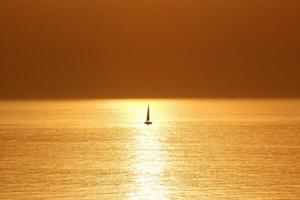 Barca a vela solitaria in mare al tramonto