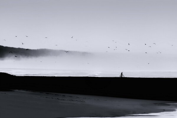 Photo sombre avec un homme au bord de la mer sur un vélo