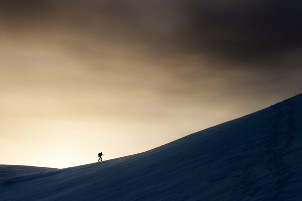 Homme marchant dans la montagne sur fond de ciel sombre
