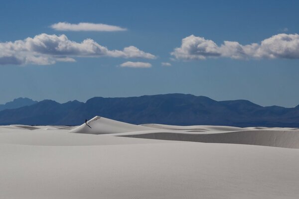 Paisaje desértico. Arenas y montañas en el horizonte. El hombre camina por el desierto