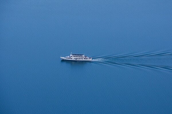 Minimalistic photo of a ship with a symmetrical train of waves