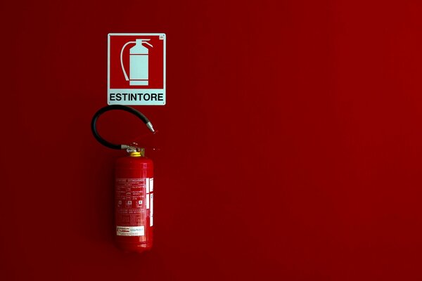 Estintore e segno estintore su sfondo rosso nel minimalismo