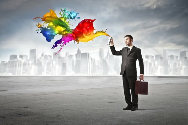 A man in glasses and a business suit sprays a spray can with rainbow red on a gray city