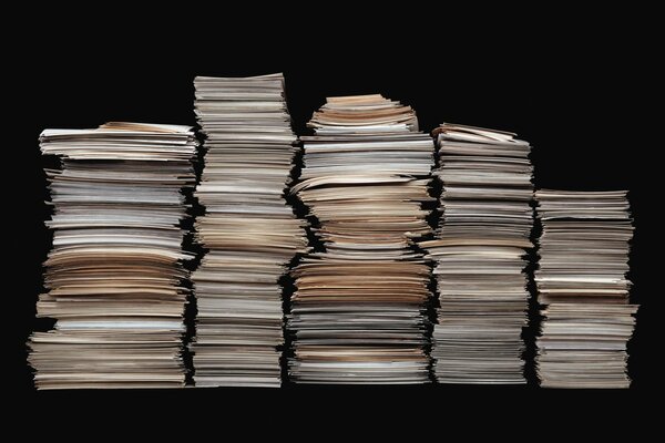 Five tall stacks of paper on a black background