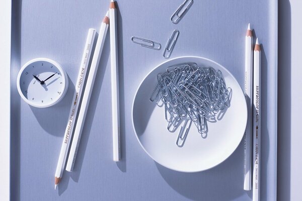 White pencils with a clock and a plate with paper clips