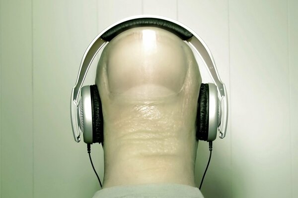 A thumb in a T-shirt listens to music with headphones