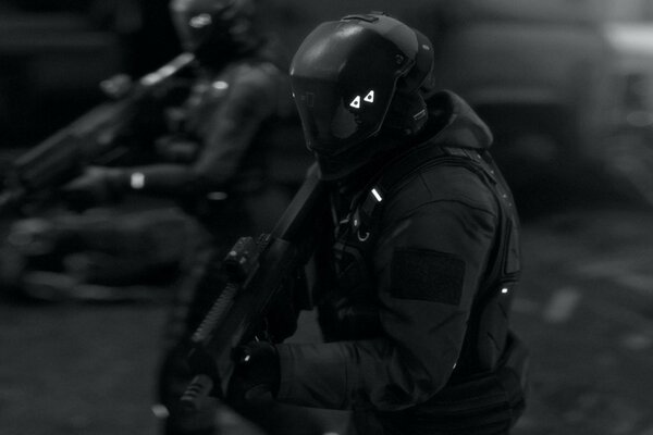 A mercenary in a bulletproof vest with a machine gun. The man in the helmet