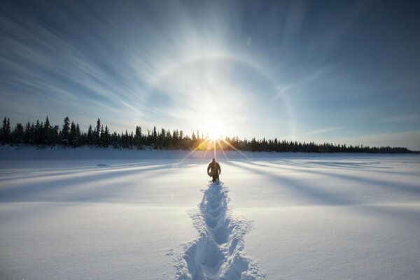 A traveler walks through snowdrifts to the sun