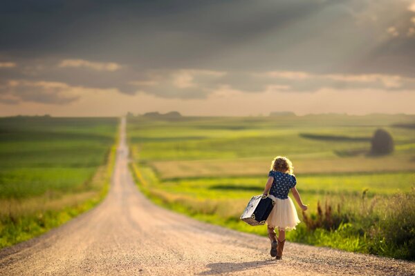 A girl with a suitcase walking along the road. The long road