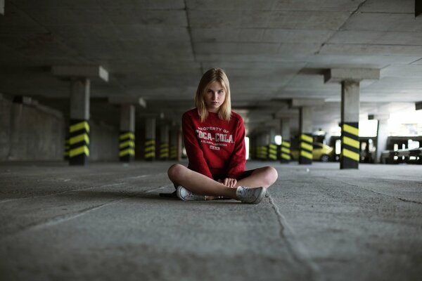 Chica sentada en el asfalto en el estacionamiento