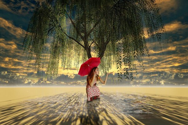 Fille avec un parapluie rouge sur un arbre dans le désert sans fond de ciel nuageux