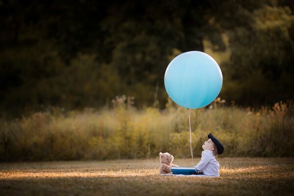 Ein Junge mit einem Teddybär schaut auf einen Ballon