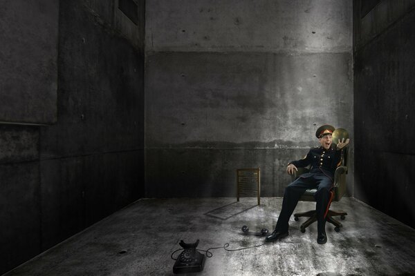 A policeman on an office chair with a black phone in a bunker