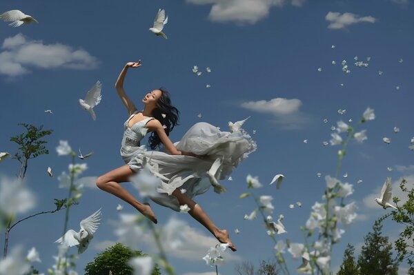 A girl with pigeons on the sky background