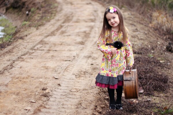 Bambina in un bel vestito e con una valigia