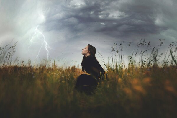 A girl in a field with lightning and wind