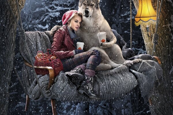 Little Red Riding hood with a wolf and a cup of coffee on a swing in winter