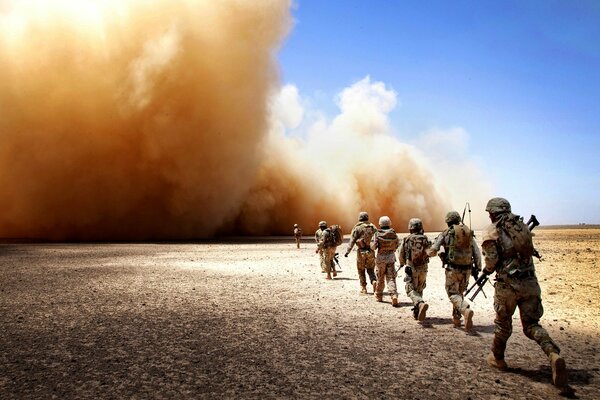 Les soldats dans le désert vont dans une tempête de poussière