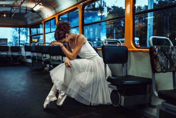 Ballerina in Tutu und Pointe fährt im Bus