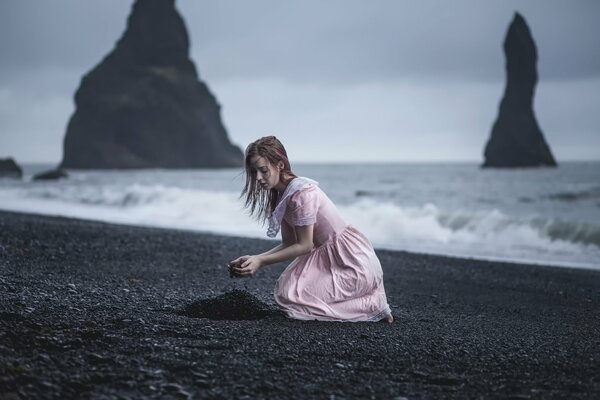 Fille sur le rivage avec du sable noir