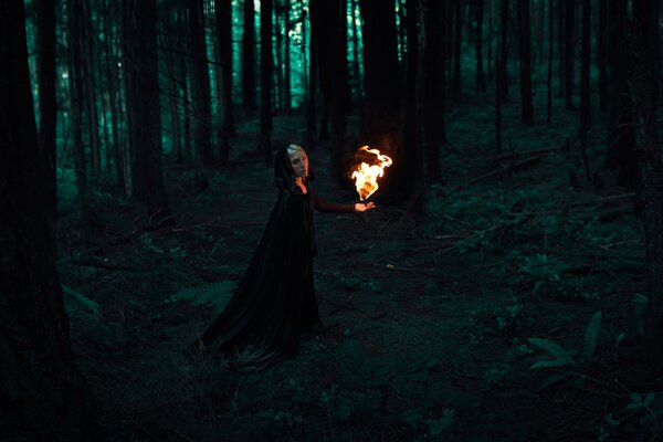 A girl with fire in a dark forest