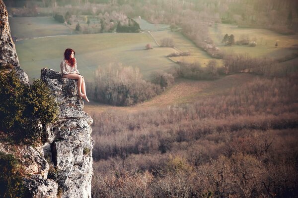 Rothaarige Mädchen sitzt auf einem Felsen