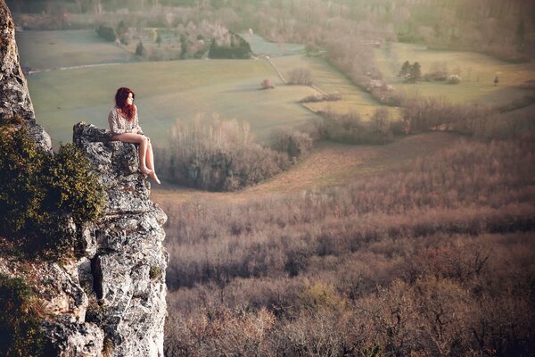 Pelirroja chica se sienta en una roca