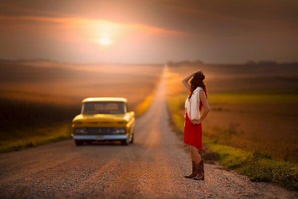 A girl in the sunset on the road. The car