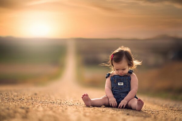 A little girl is sitting on the road