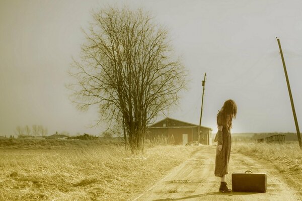 Girl on the background of a field with a suitcase