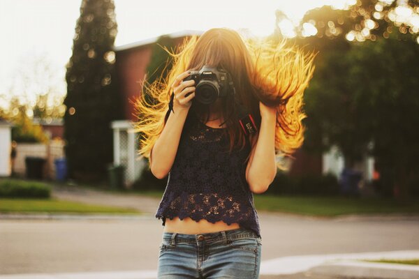 A girl in a denim skirt takes pictures with a camera