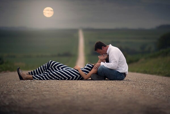 A guy and a girl are lying on the road