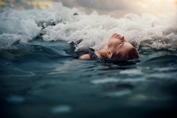 The girl is lying on her back in the surf