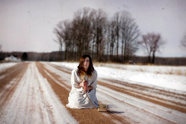 Una chica con un Teléfono con cable en un camino nevado