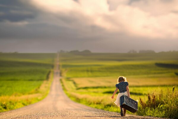 Una niña con una maleta caminando por el camino