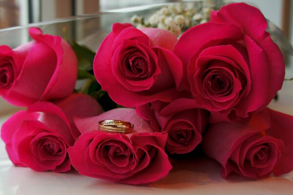 A bouquet of roses on the table. The ring lies on the bud