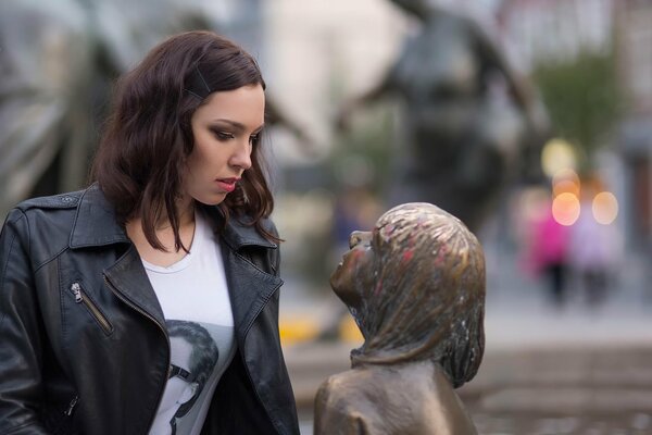 The girl looks attentively at the sculpture