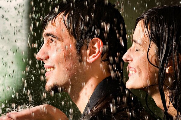 A guy and a girl smile in the rain